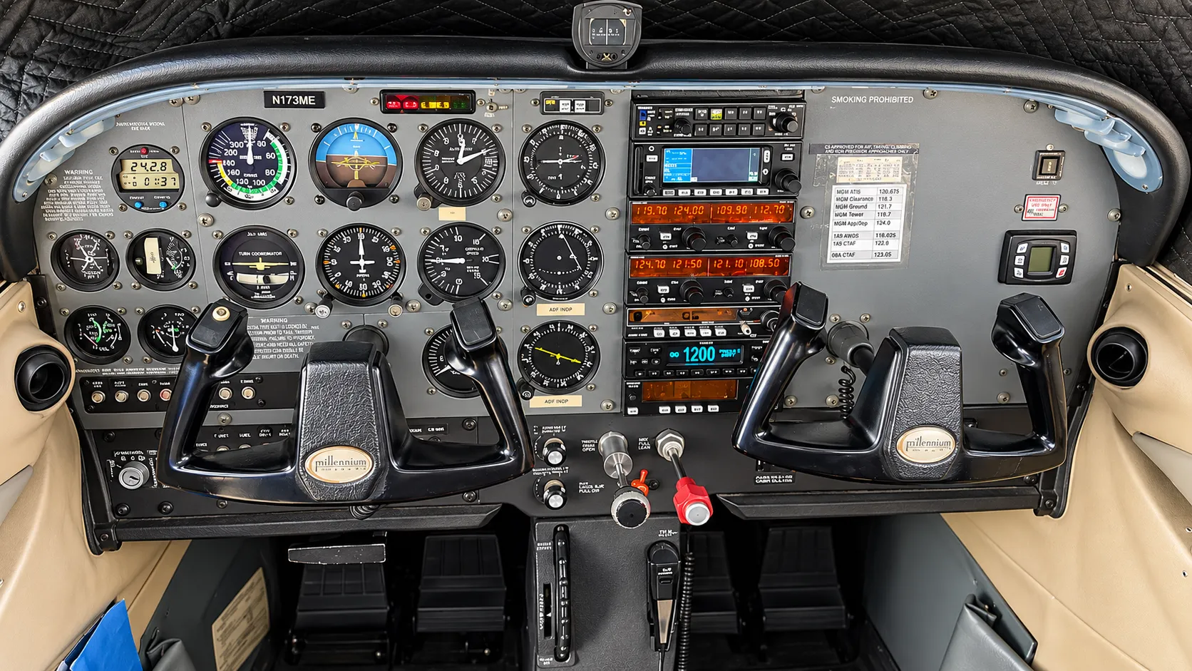 Analog general-aviation instrument panel with the six primary flight instruments on the left, an avionics stack in the centre, two control yokes, and throttle and mixture controls